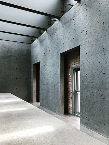 An interior photo of a sleek, modern interior with concrete floors, exposed I beams, and exposed brick.