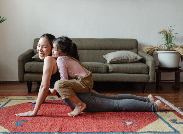 photo of girl hugging her mom while in yoga pose in living room