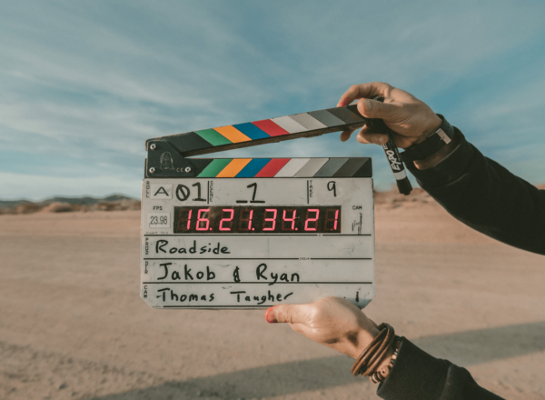 Person holding a clapperboard with a roadside at the background.